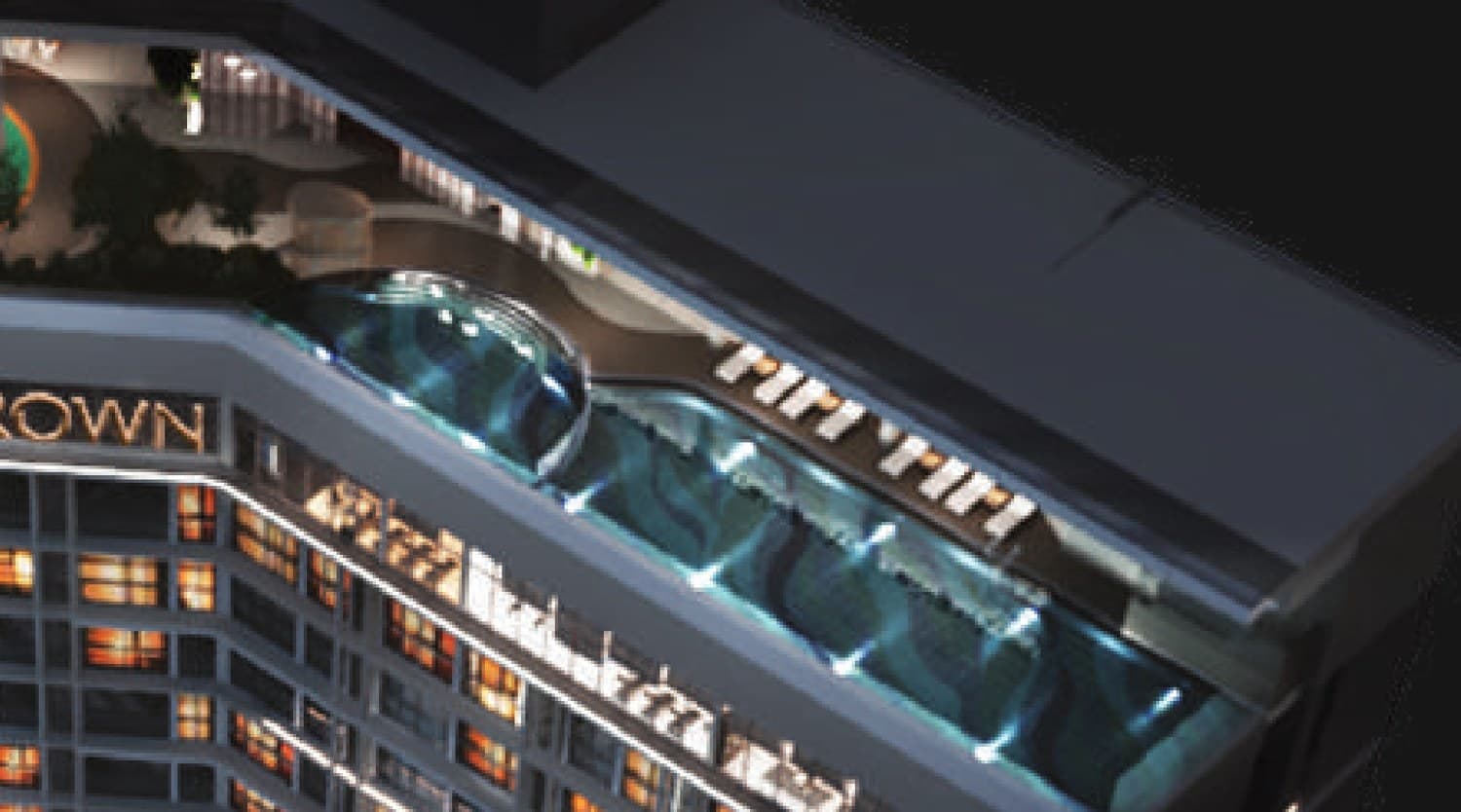 The Level 59 pool, lit from within and set hard against the parapet, with the pool deck and its run of loungers along the inner edge and the wading pool at the near end